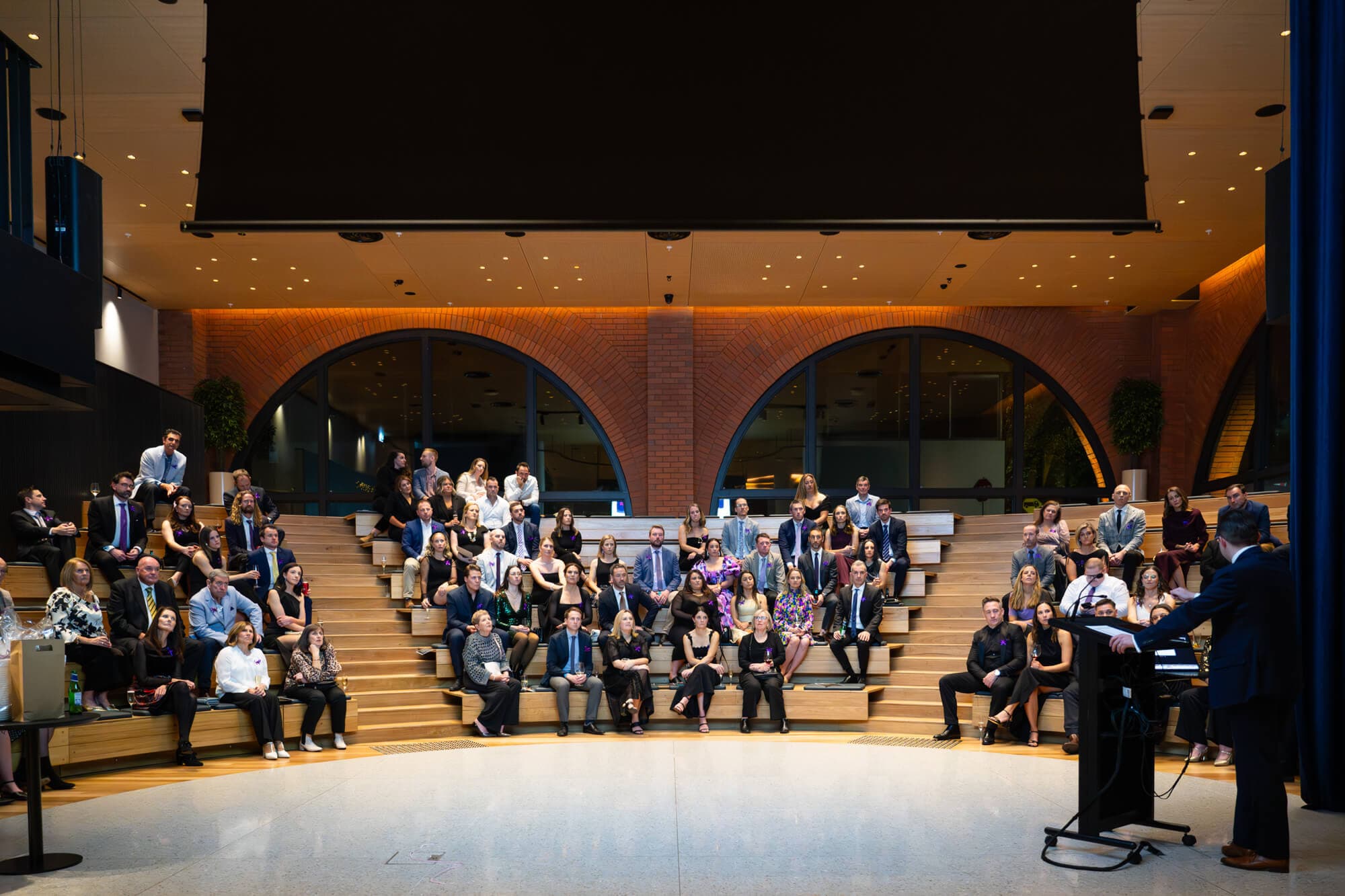 The full auditorium listening to a speaker from the tiered seats